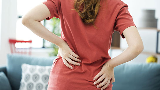 Woman holding lower back in pain before visiting Buckeye chiropractor