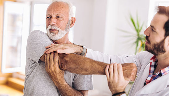 Elderly man receiving shoulder adjustment from Phoenix chiropractor